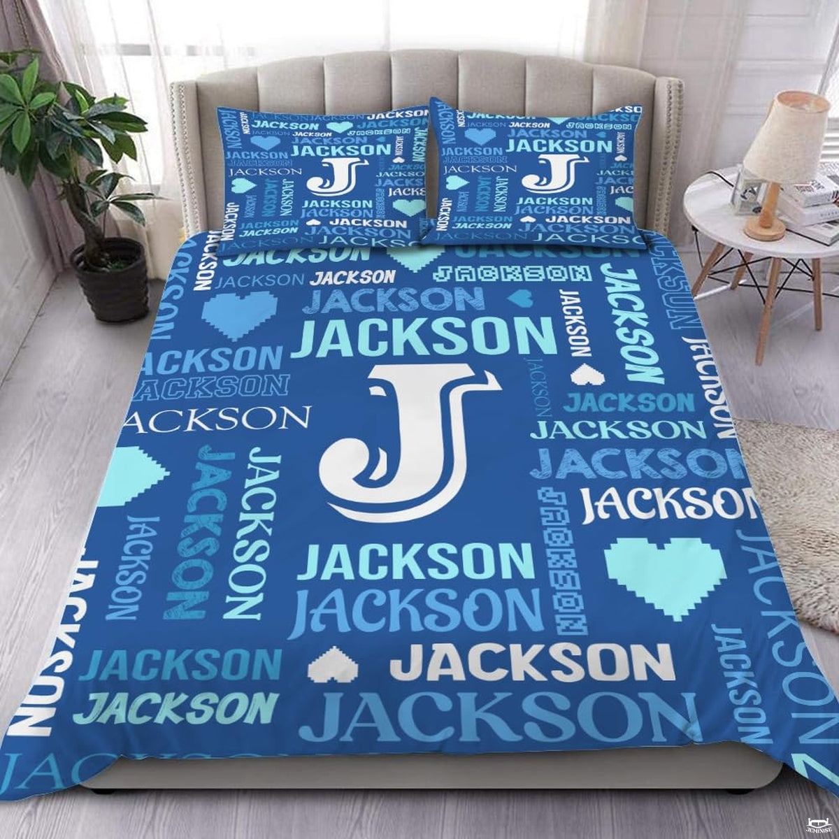 Close-up view of bedding detailing bold initial outline, pixel heart motifs, and vibrant blue typography accents
