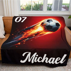 Living room display with the flaming soccer design draped over a couch beside a window.