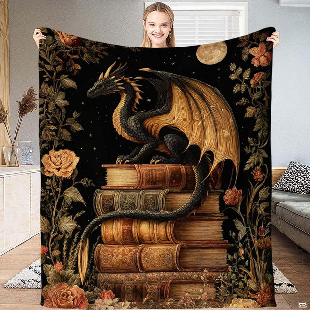 Full view of black throw blanket with golden winged dragon perched on antique books framed by rose vines and full moon.