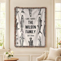 Folded vintage fish engraving throw blanket resting on wooden table displaying fish sketches