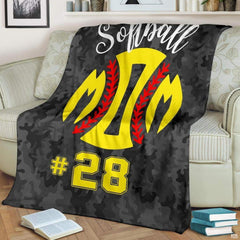 Softball blanket draped across armchair displaying bright yellow sports emblem over camouflage pattern