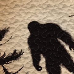 Close-up view of Bigfoot bedding showcasing golden wheat parchment, pine trees, and Sasquatch silhouette