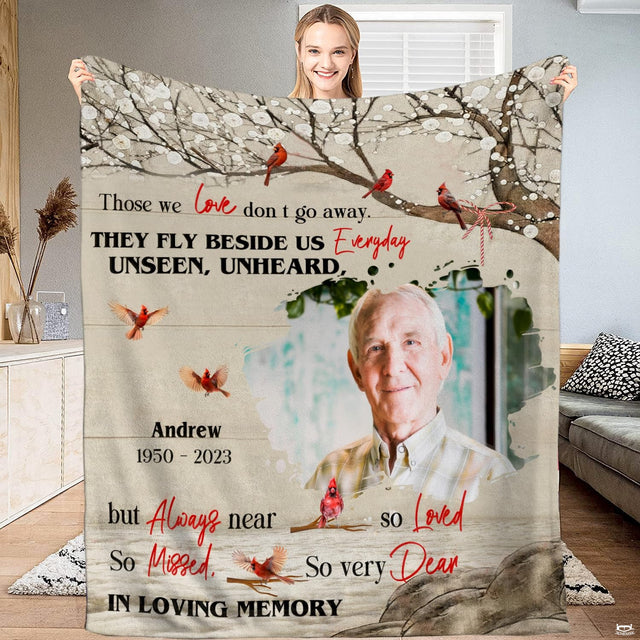 Full view of sympathy throw blanket held up, showing red cardinals in blossom branches and portrait vignette.