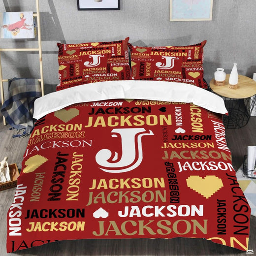 Red monogram bedding displaying crisp white initial letter surrounded by crimson and gold word-cloud typography