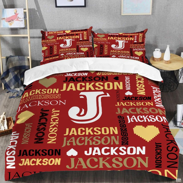 Red monogram bedding displaying crisp white initial letter surrounded by crimson and gold word-cloud typography