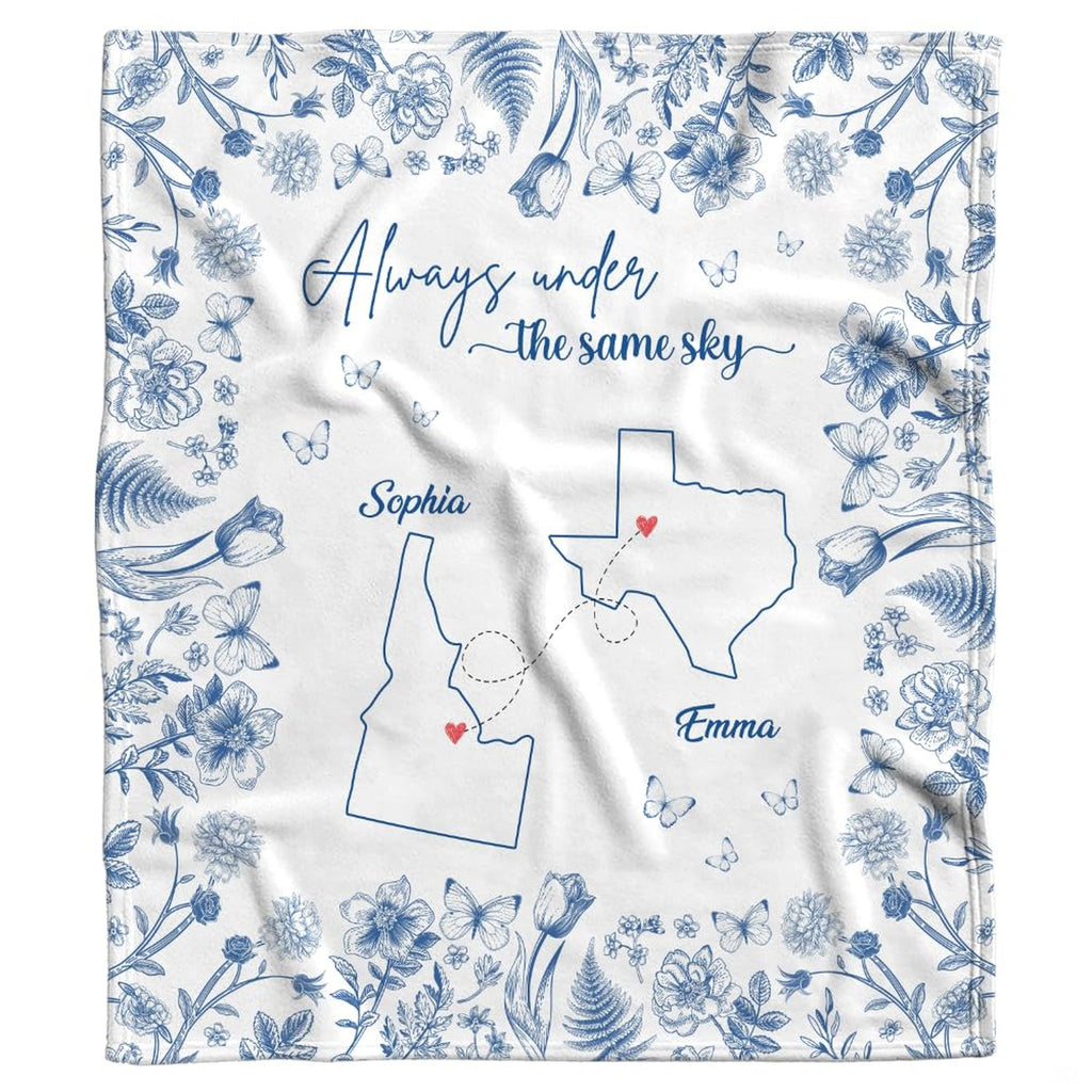 Blue botanical state map throw blanket folded neatly showing cobalt floral borders and white ground