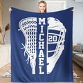 Person standing indoors holding up a sapphire lacrosse stick and helmet sports blanket.