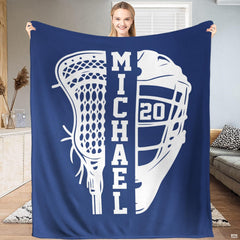Person standing indoors holding up a sapphire lacrosse stick and helmet sports blanket.