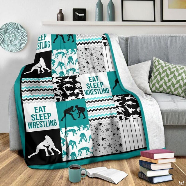 Flat layout of teal and black wrestling blanket displaying athlete silhouettes and chevron patterns.