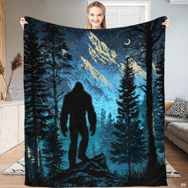 Person displaying a Bigfoot throw blanket showcasing cryptid silhouette and mountain night sky