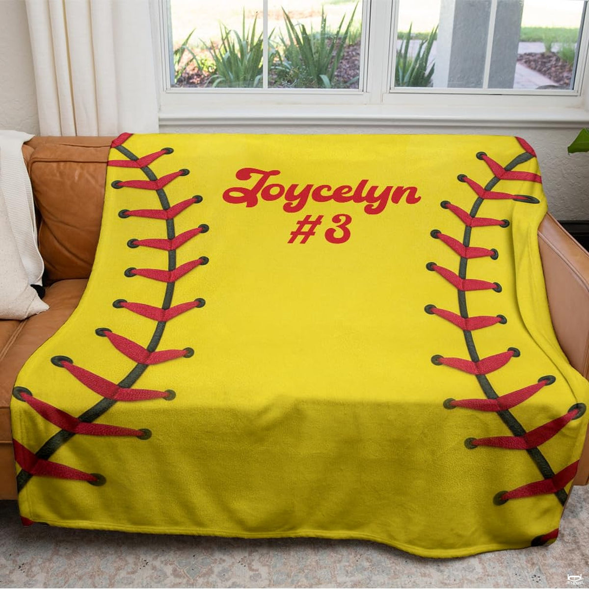 Optic yellow sports textile arranged across a brown living room couch facing a window.