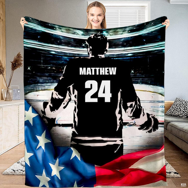 Ice hockey player standing on illuminated rink with American flag motif in deep navy and red arena lighting.