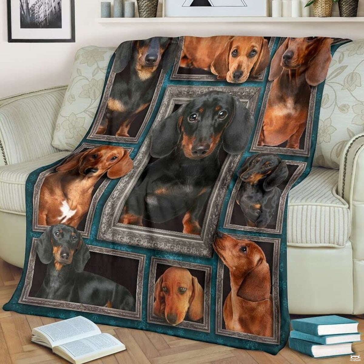Dachshund throw blanket styled across a living room sofa near stacked books and a cup.