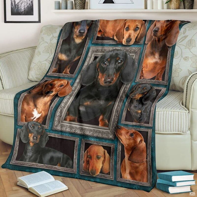 Dachshund throw blanket styled across a living room sofa near stacked books and a cup.