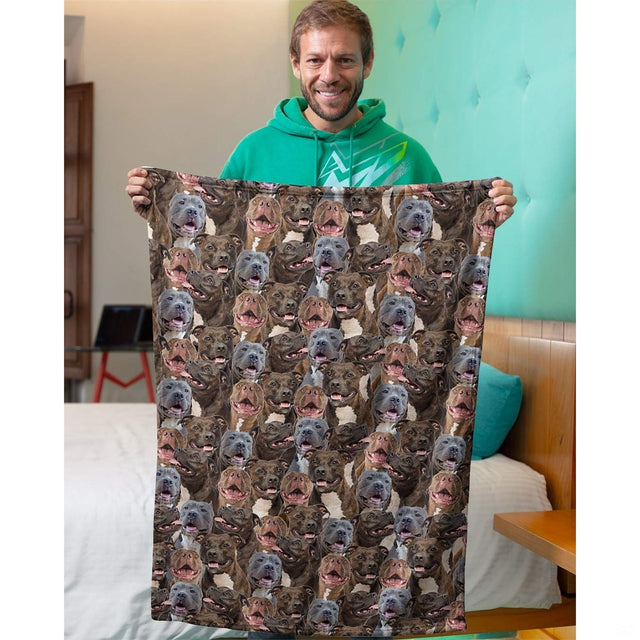 Person holding up a pitbull dog collage blanket in an indoor domestic room setting.