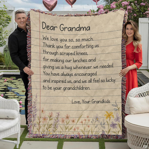 Full outdoor view of fringed throw blanket showing ruled stationery graphic, handwritten text, plus wildflowers.
