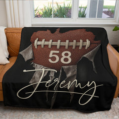 Football heart graphic throw blanket displayed neatly over a brown leather living room couch.
