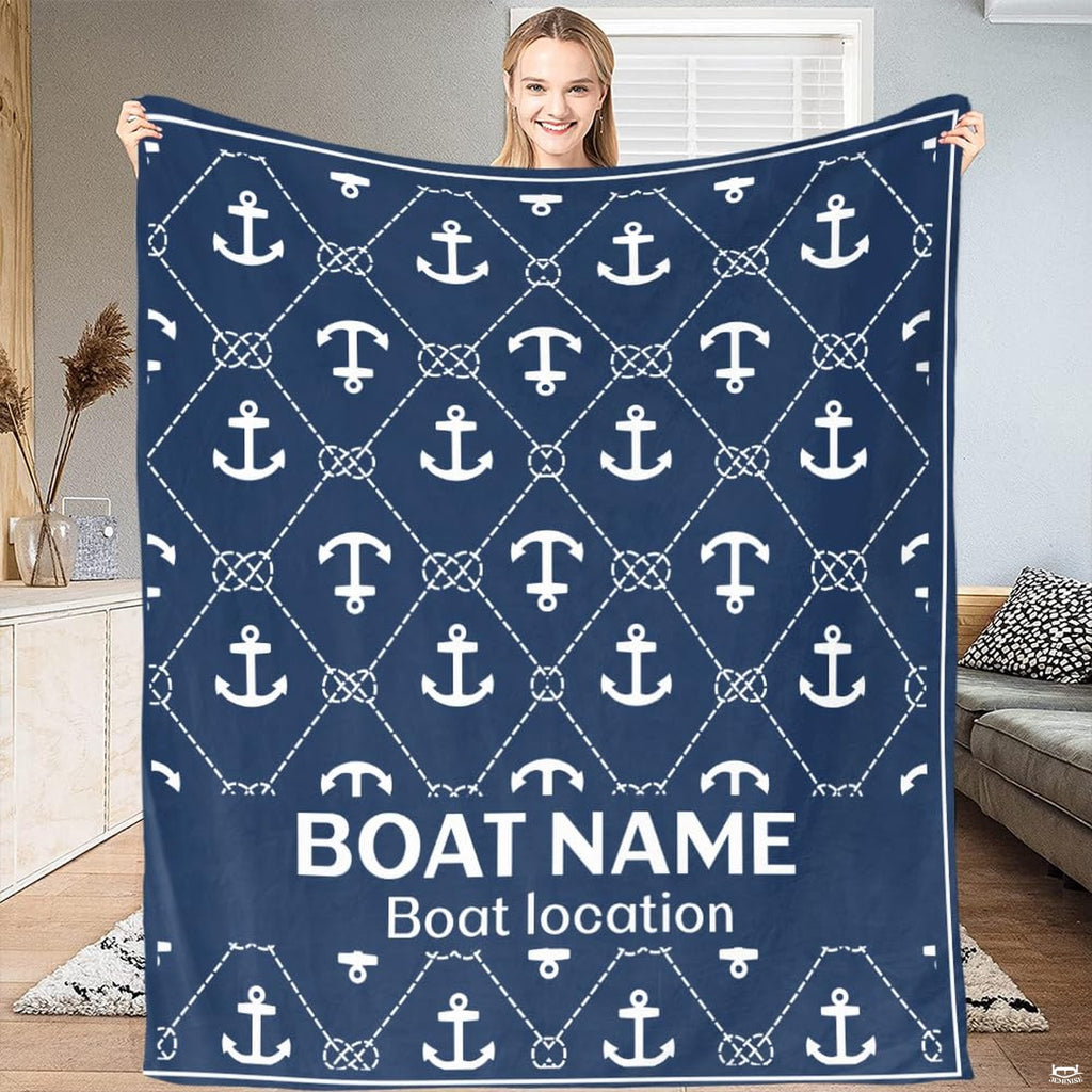 Woman displaying navy blue nautical throw blanket with white anchor and knotted rope lattice pattern.