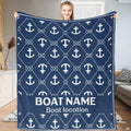 Woman displaying navy blue nautical throw blanket with white anchor and knotted rope lattice pattern.