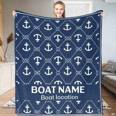 Woman displaying navy blue nautical throw blanket with white anchor and knotted rope lattice pattern.