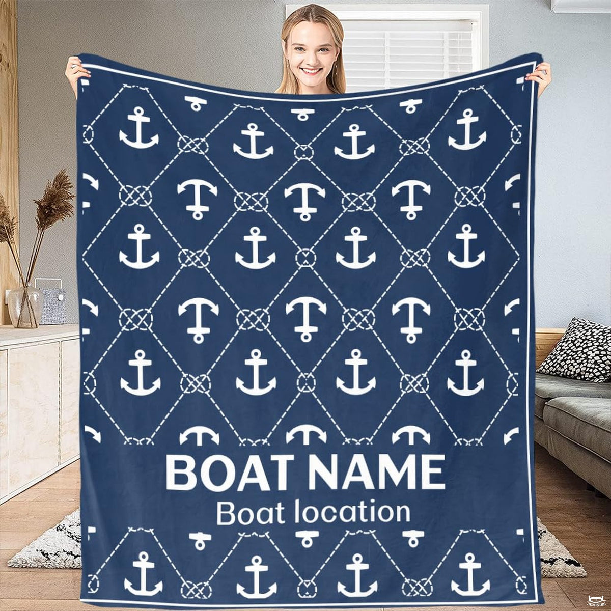 Woman displaying navy blue nautical throw blanket with white anchor and knotted rope lattice pattern.