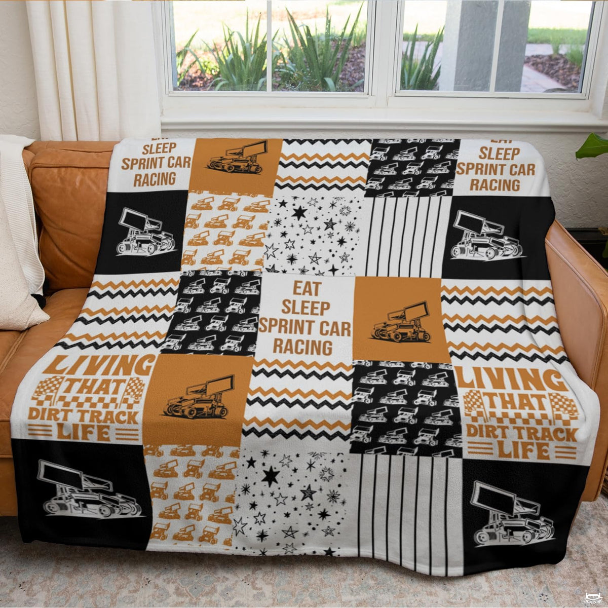Detailed perspective of the orange and black chevron zigzags and checkered flag graphics on the throw blanket