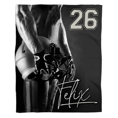 Woman holding open football player throw blanket showing monochrome gridiron athlete and helmet