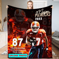 Woman displaying fiery football player graphic throw blanket with photo preview guide on football turf.