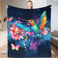 Woman holding up a dark blue blanket featuring a colorful hummingbird, pink flowers, and butterflies.