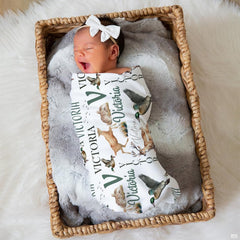 Sleeping newborn infant swaddled in woodland wildlife print lying peacefully in a woven wicker basket.