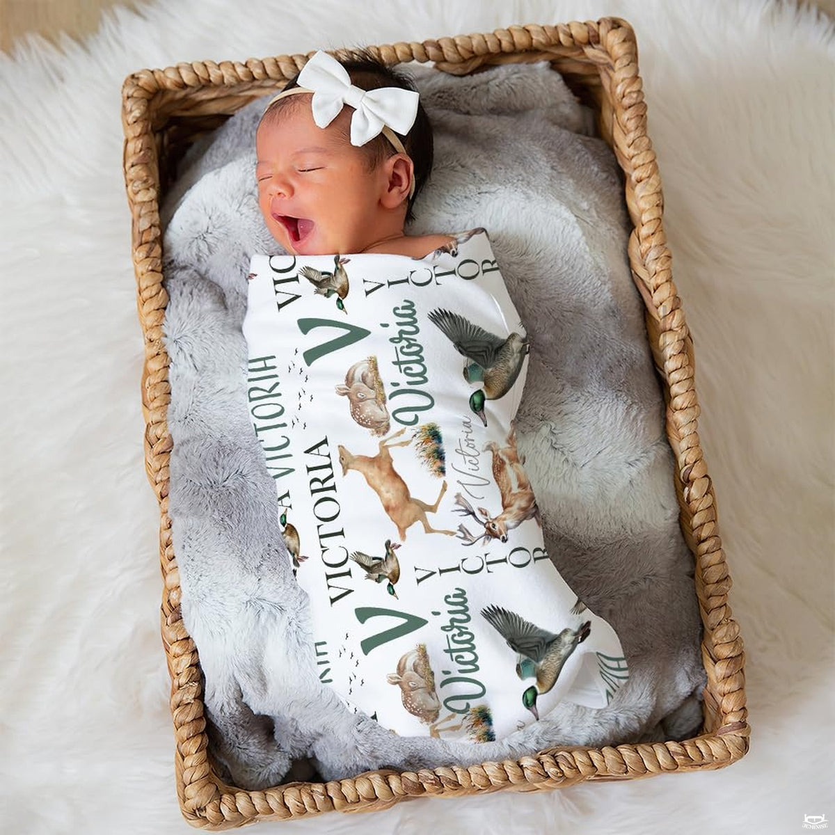 Sleeping newborn infant swaddled in woodland wildlife print lying peacefully in a woven wicker basket.