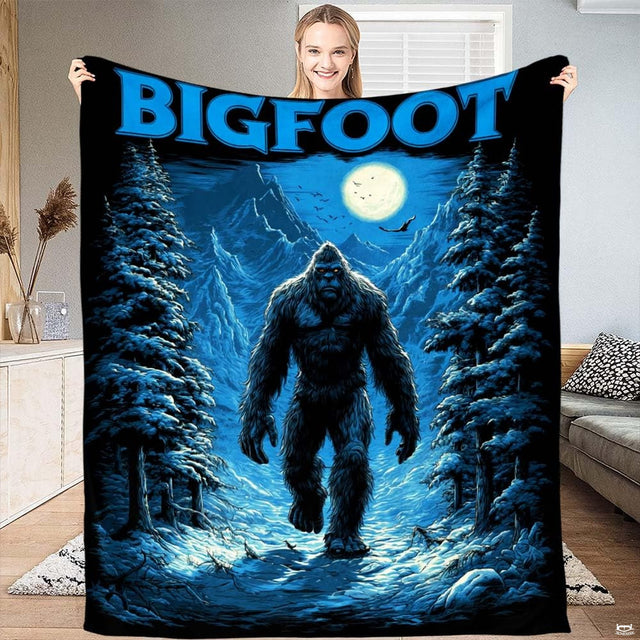 Winter Bigfoot throw blanket featuring Sasquatch walking down snowy mountain path between pine trees under full moon
