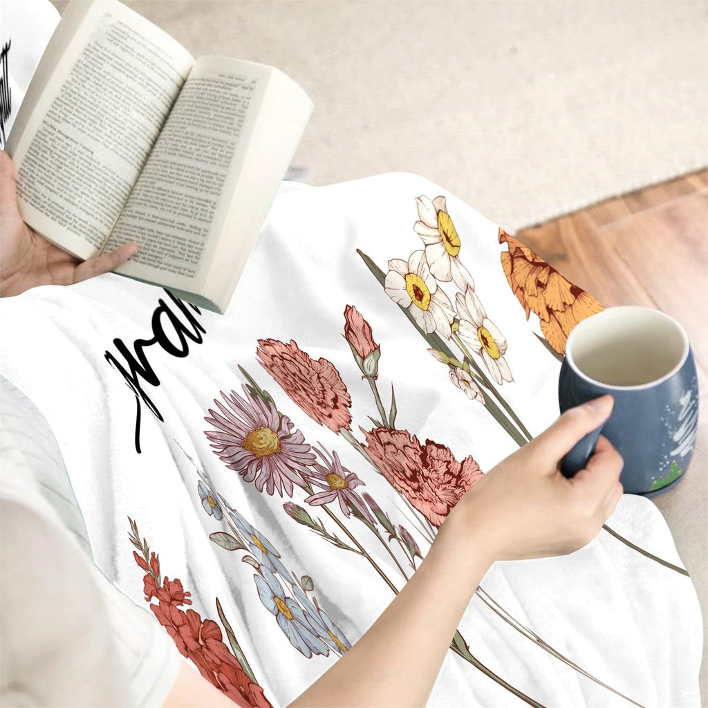 Person reading a book with the illustrated birth month flower graphic draped across lap.