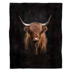 Dramatic portrait of Scottish Highland cow with curved horns emerging from black background, view 1.
