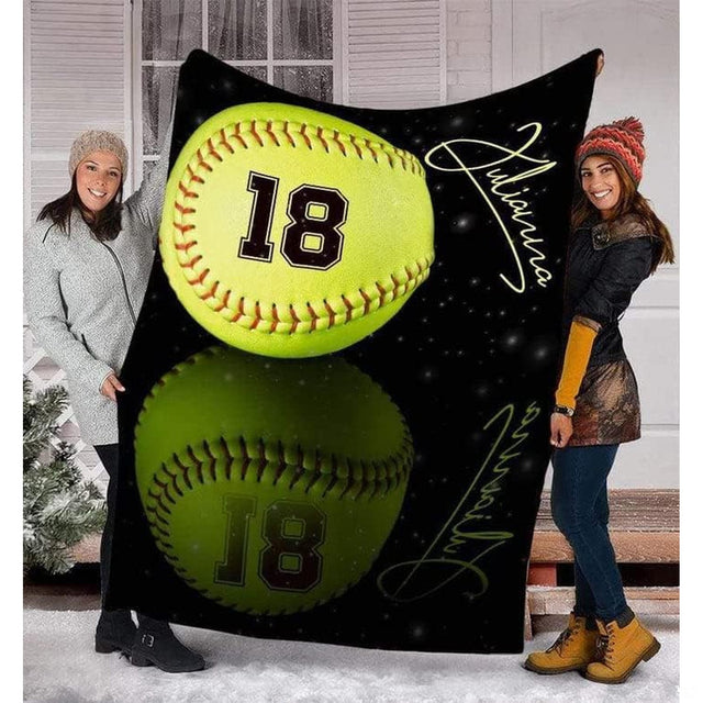 Softball blanket held by two women showcasing optic yellow ball design outdoors in snowy yard