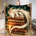 Full view of white fantasy dragon curled asleep on stacked antique books with candlelit glow and illuminated border.