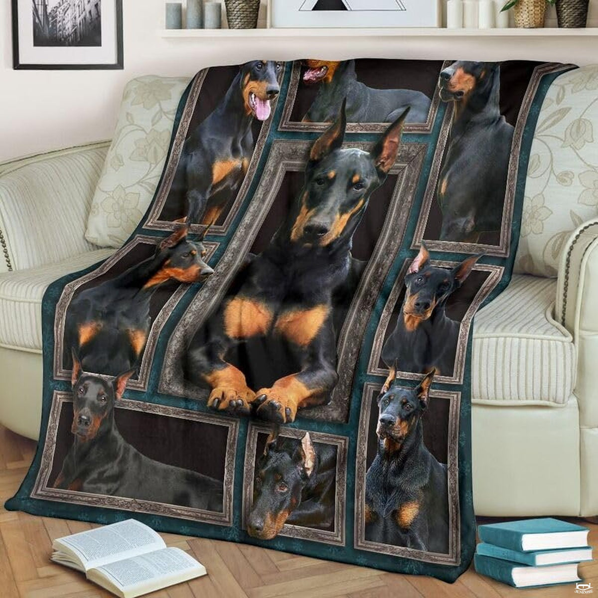 Doberman Pinscher throw blanket styled across a living room sofa near stacked books and a cup.