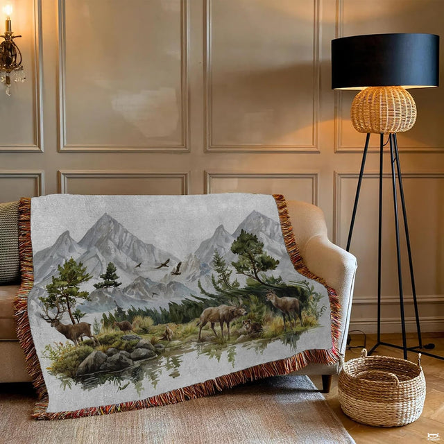 Close-up of watercolor mountain peaks, evergreen pines, and grazing deer on a wilderness blanket