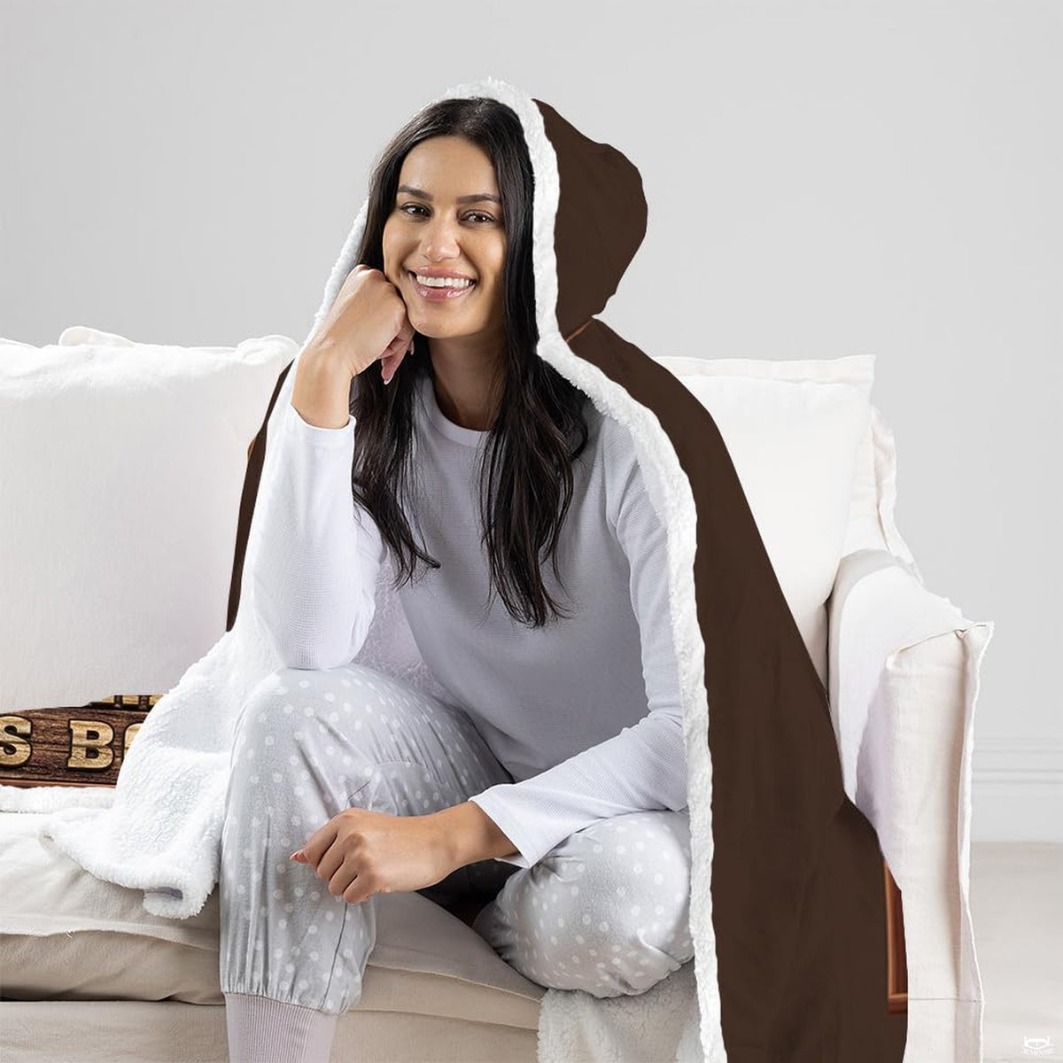 Reader throw blanket draped over a living room couch beside a full bookshelf