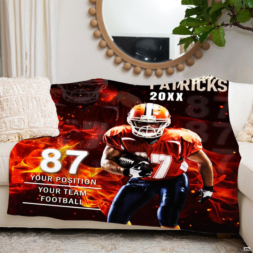 Fiery football player graphic throw blanket displayed over white couch beneath round wall mirror.