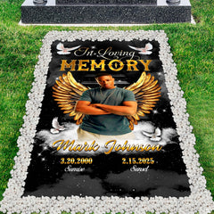 Top-down cemetery perspective showing celestial angel wings tribute placed before a polished headstone.