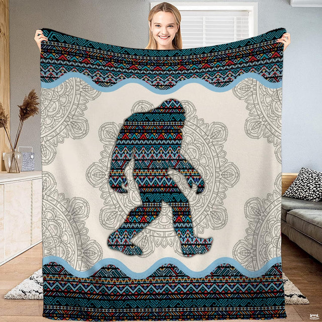 Bigfoot blanket held open displaying the tribal geometric Sasquatch silhouette and cream mandala background.