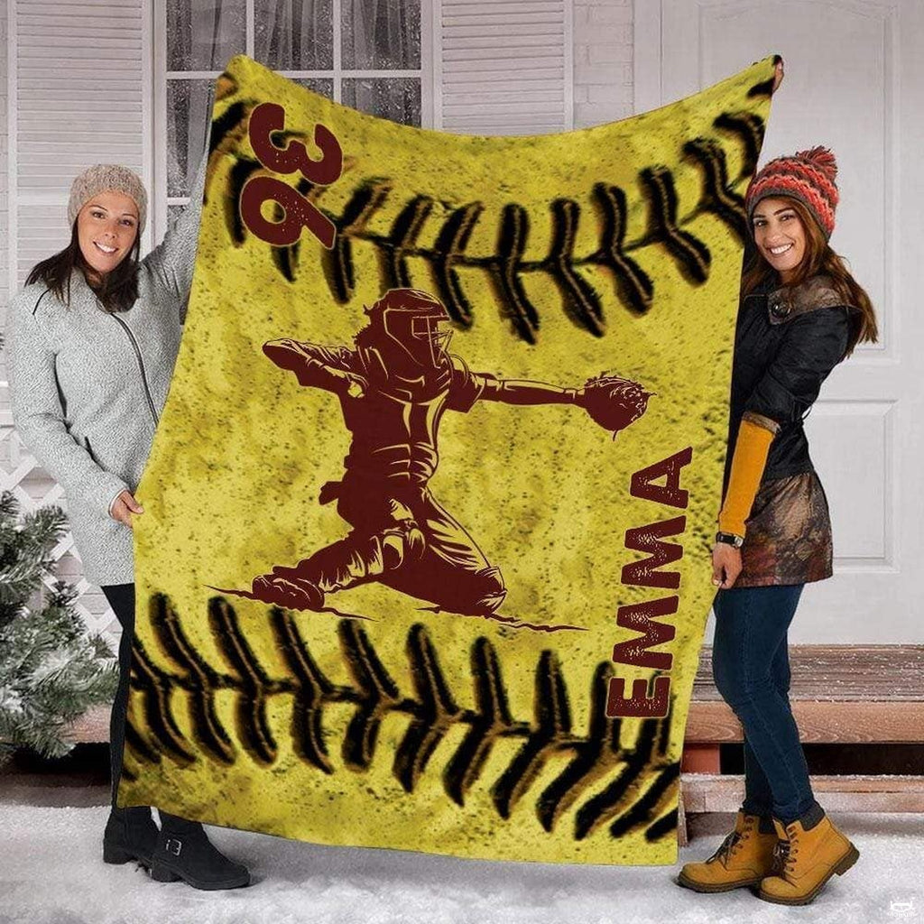 Two people standing outdoors in snow holding up the yellow softball catcher print.