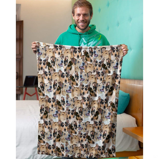 Model holding up a collie dog collage blanket in an indoor bedroom setting.