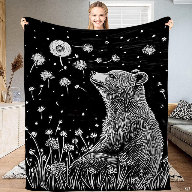 Monochrome woodcut of gentle bear in wildflower meadow watching floating dandelion seeds, view 1.