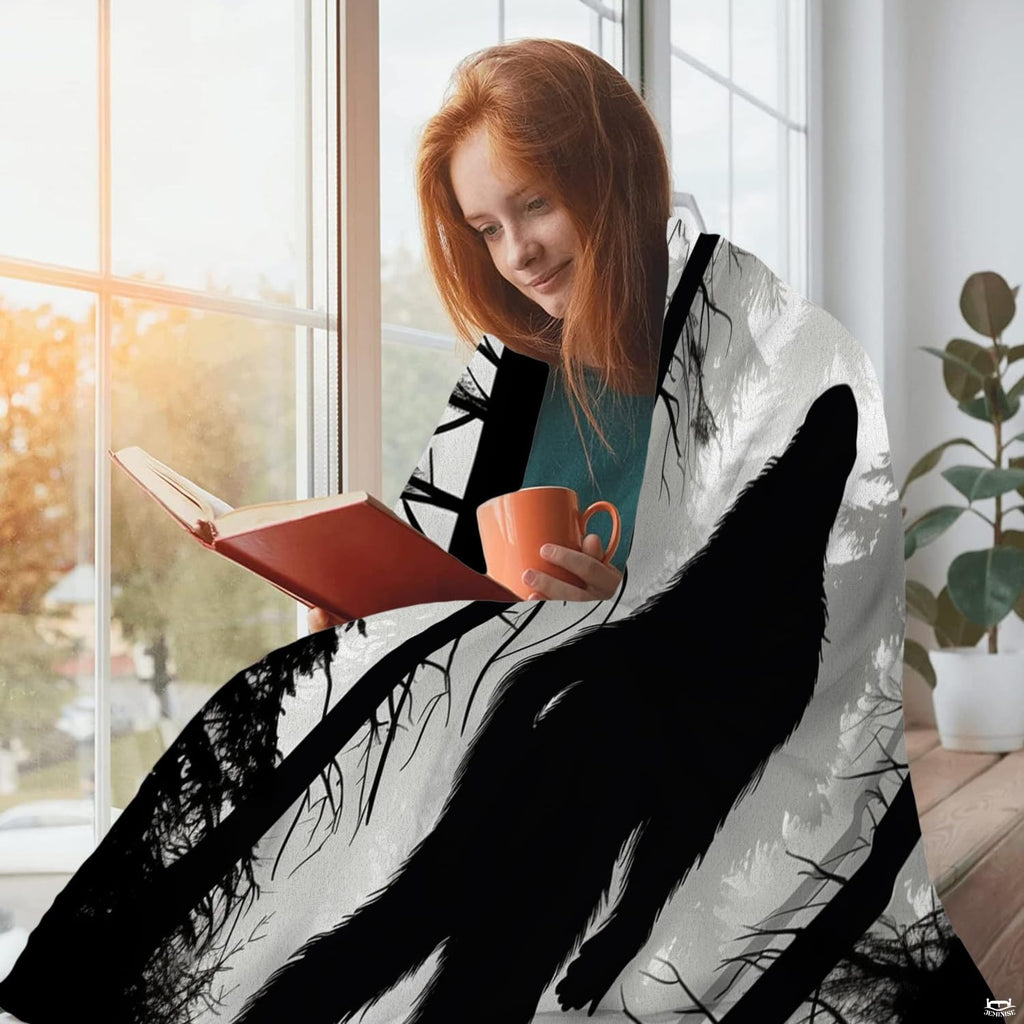 Person sitting beside a window with a mug and book while draped in the misty forest Bigfoot textile.