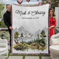 Couple holding woodland mountain throw blanket with watercolor deer, pine forest, and colorful fringed edges