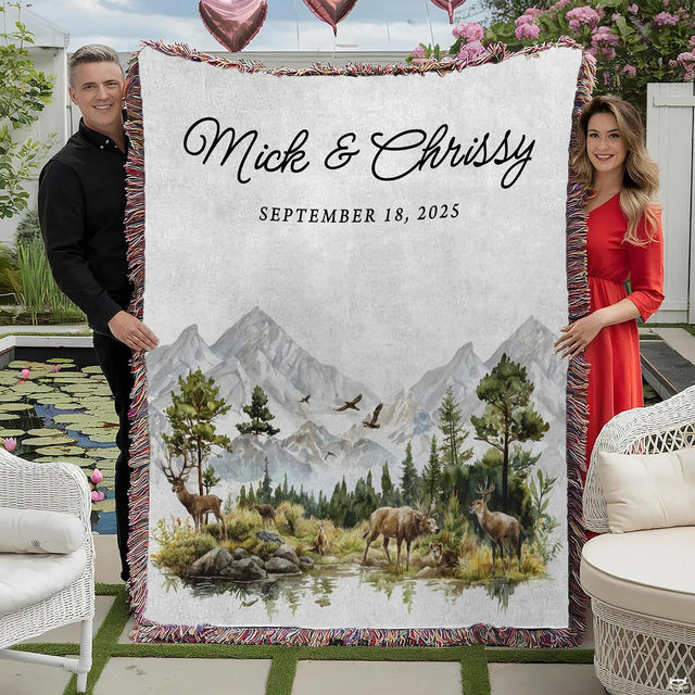 Couple holding woodland mountain throw blanket with watercolor deer, pine forest, and colorful fringed edges