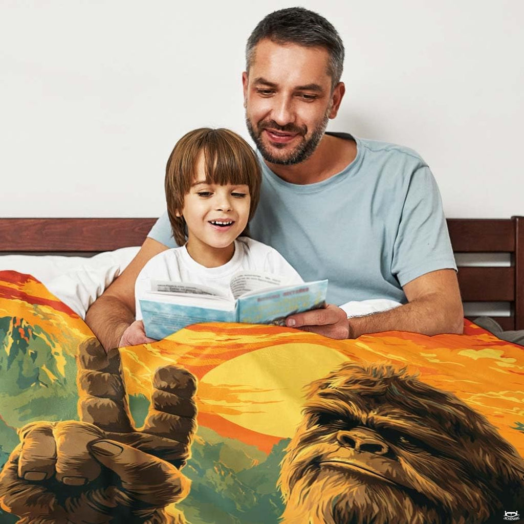Parent and child reading a book together beneath the colorful sunset Bigfoot print in an indoor setting.