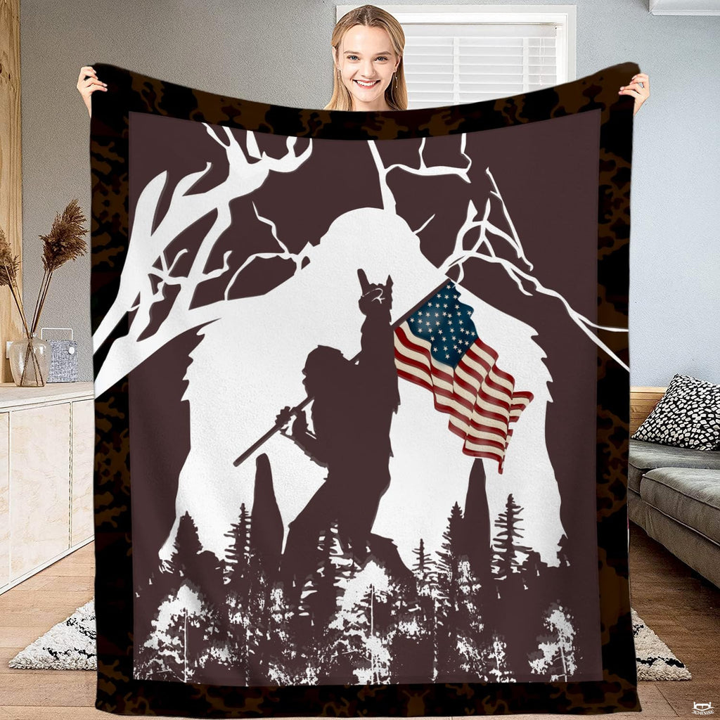 Patriotic Bigfoot blanket held open displaying the American flag Sasquatch graphic and camo border.